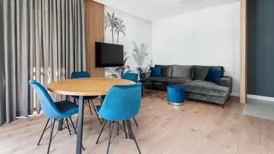 a living room with a table and blue chairs at Novum City Center, Sun & Snow in Kraków