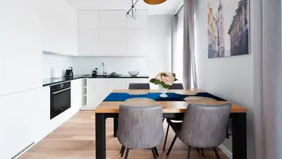 a kitchen and dining room with a wooden table and chairs at Novum City Center, Sun & Snow in Kraków