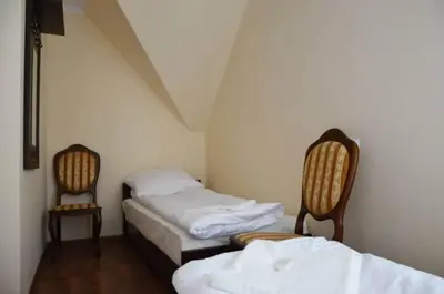 a room with two beds and two chairs in it at Pokoje Gościnne w Ratuszu in Ogrodzieniec