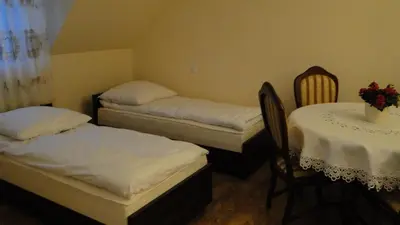 a room with two beds and a table and chairs at Pokoje Gościnne w Ratuszu in Ogrodzieniec