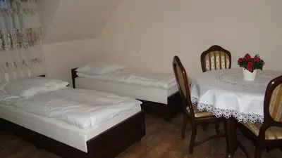 a room with two beds and a table and chairs at Pokoje Gościnne w Ratuszu in Ogrodzieniec