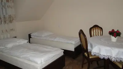 a room with two beds and a table and chairs at Pokoje Gościnne w Ratuszu in Ogrodzieniec