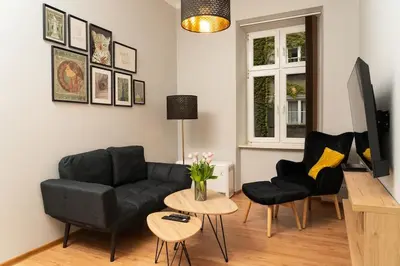 a living room with a black couch and two chairs at Asnyka Old Town in Kraków