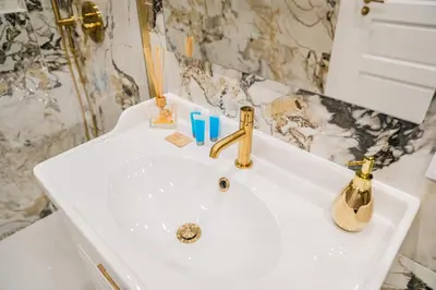 a white bathroom sink with a gold faucet at Kazimierza Wielkiego Luxury Apartment by BookingHost in Kraków