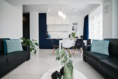 a living room with black couches and a kitchen at Pankrac 2 by Housine in Zator