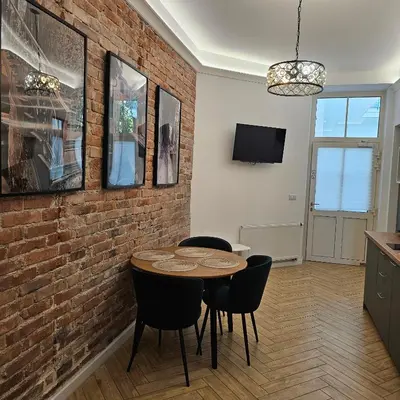 a dining room with a brick wall and a table and chairs at JUWEL Apartments Kraków z widokiem na Wawel ap 31 in Kraków