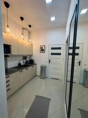 a large kitchen with white tile floors and white cabinets at Salt INN Apartments No 1 in Wieliczka