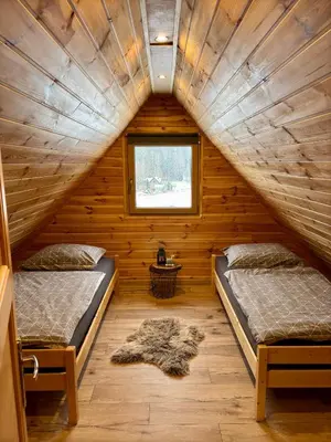 two beds in a log cabin with a window at Domki na granicy - Kocoń in Jeżowski Dział