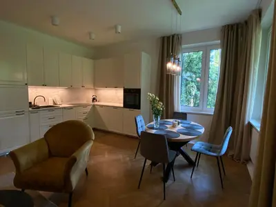 a kitchen and dining room with a table and chairs at Comfort Garden View Apartment in Kraków
