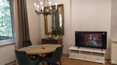 a dining room with a table and a television at Comfort Garden View Apartment in Kraków