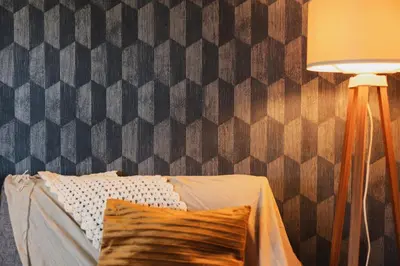 a bedroom with a bed and a lamp and a wall at Zakątek Apartments in Kraków