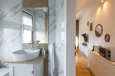 a white bathroom with a sink and a mirror at Zakątek Apartments in Kraków