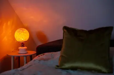 a lamp on a table next to a bed at Zakątek Apartments in Kraków