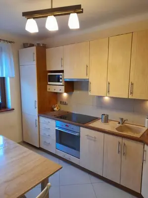 a kitchen with wooden cabinets and a stove top oven at Bronowice- parter domu in Kraków