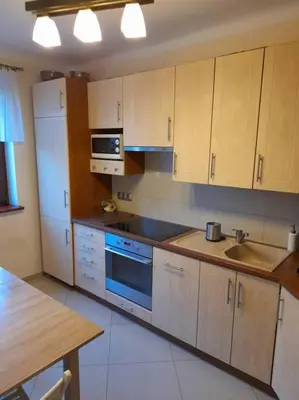 a kitchen with wooden cabinets and a blue stove top oven at Bronowice- parter domu in Kraków