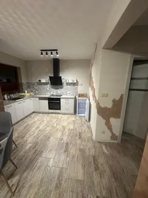 a kitchen with white cabinets and a wooden floor at Domek w Koszarawie Bystrej in Koszarawa