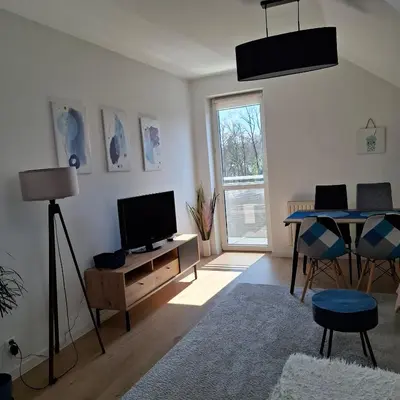 a living room with a television and a table at Apartament Pastelowy in Kraków