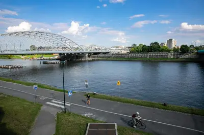 a bridge over a river with two people on a bike at Vistula River Modern Apartment by BookingHost in Kraków