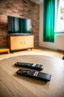 two remote controls sitting on a table in front of a television at Vistula River Modern Apartment by BookingHost in Kraków