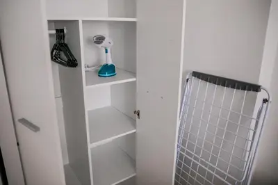 a white closet with a blue vase on a shelf at Vistula River Modern Apartment by BookingHost in Kraków