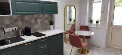 a kitchen with green cabinets and a table and chairs at Juwel Apartments Kraków z widokiem na Wawel 44 in Kraków