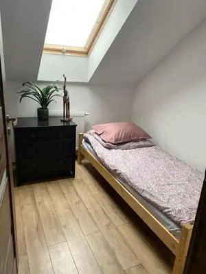 a bedroom with a bed and a dresser and a window at Noclegi Grojec in Grojec