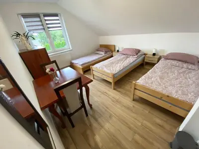 a room with two beds and a table and a desk at Noclegi Grojec in Grojec