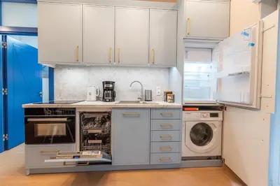 a kitchen with white cabinets and a washer and dryer at City Lights Mostowa 6 in Kraków