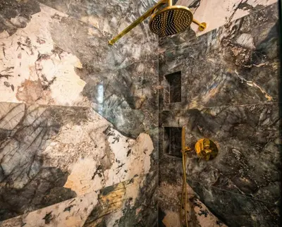 a bathroom with a shower with a stone wall at City Lights Mostowa 6 in Kraków