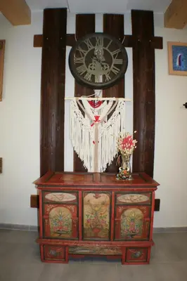 a wooden dresser with a clock on a wall at Apartamenty Siedlisko pod Aniołem in Zubrzyca Górna