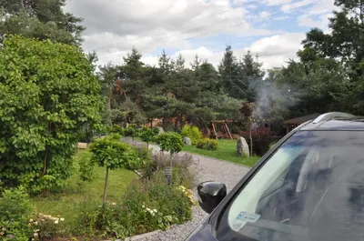a car parked next to a garden with smoke coming out at Apartamenty Siedlisko pod Aniołem in Zubrzyca Górna