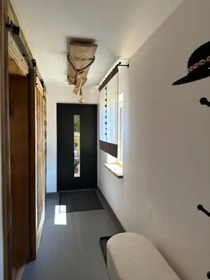a hallway with white walls and a black door at Rajskie wzgórze słoikowo in Szczawa