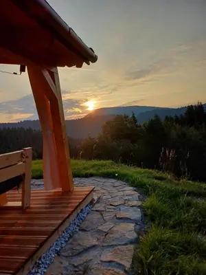 a porch of a cabin with a sunset in the background at Rajskie wzgórze słoikowo in Szczawa
