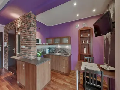 a kitchen with purple walls and a tv on the wall at Beauty of Krakow Studio in Kraków