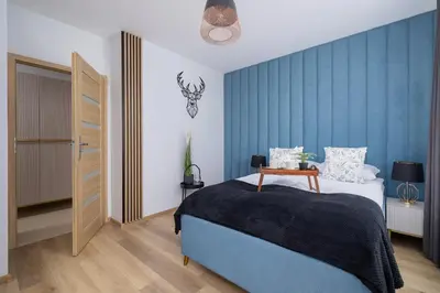 a bedroom with a bed and a blue wall at Osiedle Avia Harmonious Apartment with Balcony Cracow by Renters Prestige in Kraków
