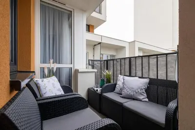 two wicker chairs sitting on a balcony at Osiedle Avia Harmonious Apartment with Balcony Cracow by Renters Prestige in Kraków