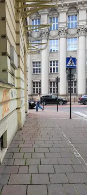 a person walking down a sidewalk in front of a building at TLC Apartments Cracow in Kraków