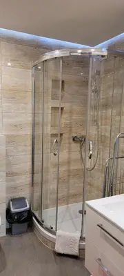 a shower stall in a bathroom with a wooden wall at TLC Apartments Cracow in Kraków