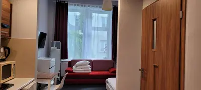 a living room with a red chair and a window at TLC Apartments Cracow in Kraków