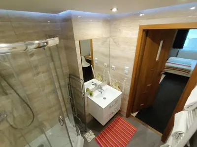 a bathroom with a sink and a shower and a mirror at TLC Apartments Cracow in Kraków
