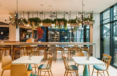a restaurant with tables and chairs and a bar at MEININGER Kraków Centrum in Kraków