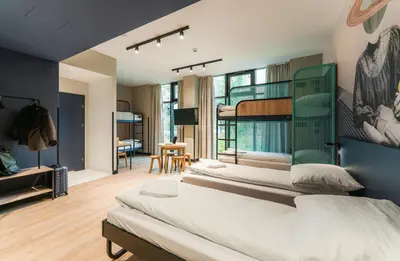 a bedroom with three beds and a room with a desk at MEININGER Kraków Centrum in Kraków