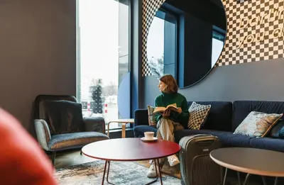 a woman sitting on a couch in a living room at MEININGER Kraków Centrum in Kraków