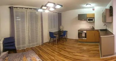a living room with a kitchen and a table with chairs at Mini Apartament Kraków PN / Cracow NORTH z parkingiem in Kraków