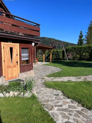 a stone path leading to a house with a wooden door at Domek do wynajęcia in Poręba Wielka