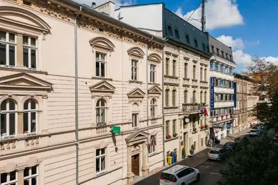 a large white building with cars parked on a street at Great apartment in the Old Town in Kraków