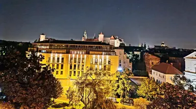 a yellow building in front of a city at night at Juwel Apartments Kraków z widokiem na Wawel ap 47 in Kraków