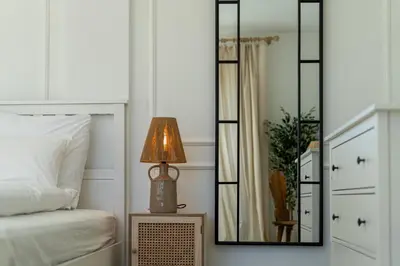 a bedroom with a mirror and a lamp on a night stand at Dom pod Lipą in Łyczanka