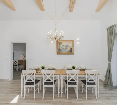 a white dining room with a wooden table and chairs at Dom pod Lipą in Łyczanka