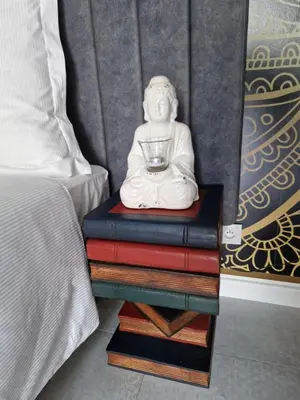 a statue sitting on a stack of books next to a bed at JUWEL Apartments Kraków Indyjski ap 29 in Kraków